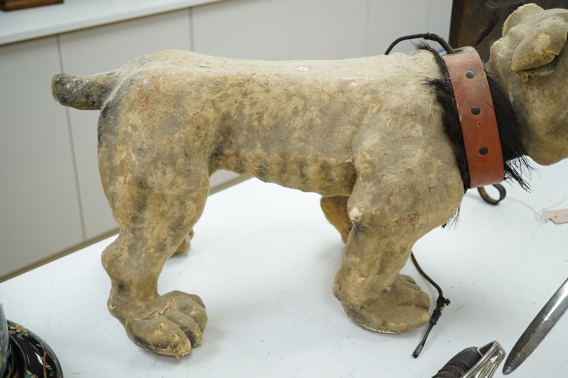 A French papier mache bulldog with bark effect, 66cm long, 35cm high. Condition - poor, some mis-shaping and part of muzzle, nose and ears missing